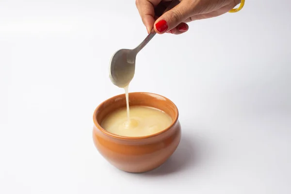 stock image Pure cow ghee in ceramic bowl on white background with ghee spoon in hand