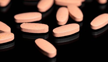 Yansıtıcı siyah arkaplan üzerine çoklu vitamin tabletini kapat