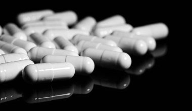 Makro, siyah arka planda beyaz ağrı kesici kapsülünü kapat.