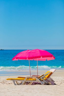 Plastik şezlonglar ve şemsiyeler Camps Bay, Cape Town 'daki kumlu sahilde.