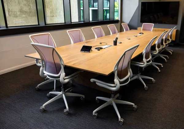 Empty executive boardroom with wooden table and fancy chairs on wheels