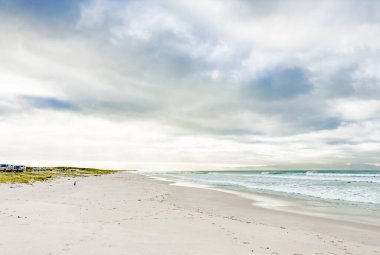 Cape Town, Güney Afrika 'da bulutlu bir sabahta kumlu güzel bir sahil.