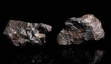 Makro, siyah yansıtıcı arka planda izole edilmiş hammadde Manganez Ore kayasının görüntüsünü kapat