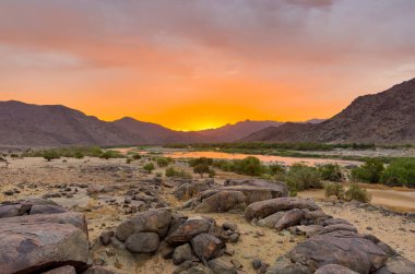 Güney Afrika 'nın kurak bölgesi olan Richtersveld Ulusal Parkı' ndaki Tatasberg kamp alanından gün batımında Orange Nehri manzarası