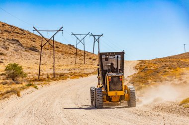 Richtersveld, South Africa - March 11, 2024: Large Caterpillar gravel dirt road grader smoothing out a road surface clipart