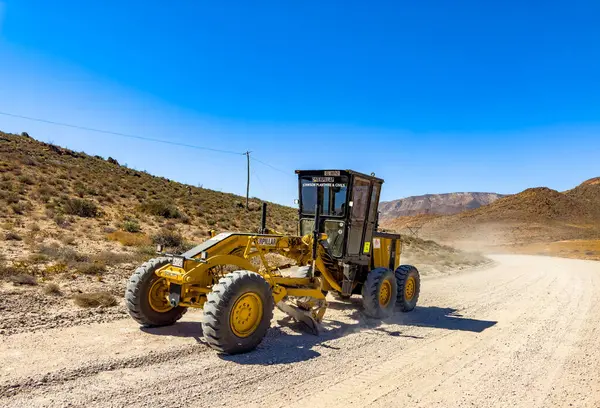 stock image Richtersveld, South Africa - March 11, 2024: Large Caterpillar gravel dirt road grader smoothing out a road surface