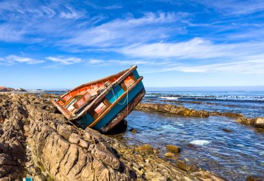 Shipwrecked diamond mining vessel on rocky shoreline in small West Coast town of Port Nolloth, South Africa clipart