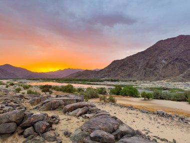 Güney Afrika 'nın kurak bölgesi olan Richtersveld Ulusal Parkı' ndaki Tatasberg kamp alanından gün batımında Orange Nehri manzarası