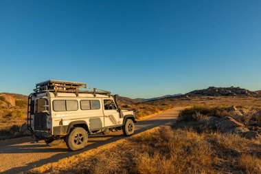 Namaqualand, Güney Afrika - 9 Mart 2024: Eski Land Rover Defender kurak bölgede bir çakıl yoluna park etti