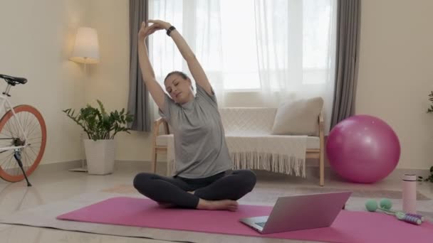 Medium Wide Shot Woman Sitting Exercise Mat Watching Online Stretching — Stock video