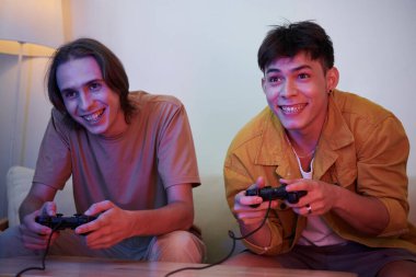 Excited cheerful best friends playing videogame at home