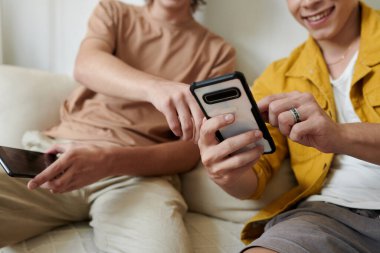 Closeup image of young man showing new meme on smartphone to best friend