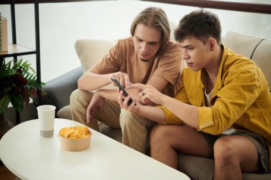 Young men exploring new mobile application on smartphone