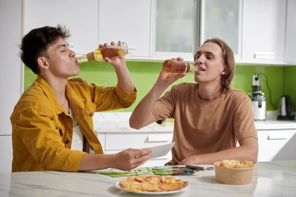 Young People Drinking Beer Eating Snacks Sitting Kitchen Table — Stockfoto