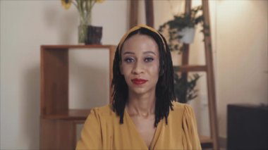 Portrait of beautiful African American woman with braided hair and red lips posing for camera at home
