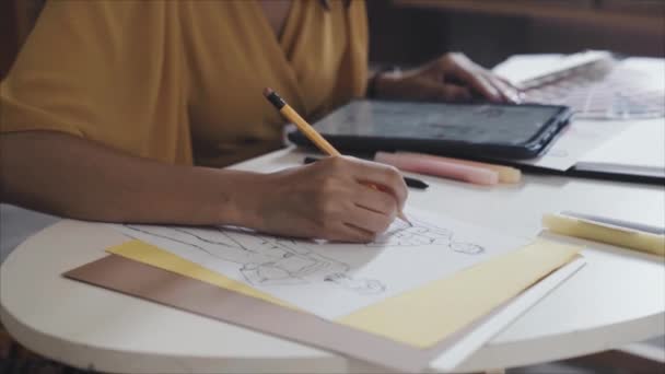 紙に鉛筆でファッションスケッチを描く女性デザイナーのトリミングショットやデジタルタブレットを使用して — ストック動画