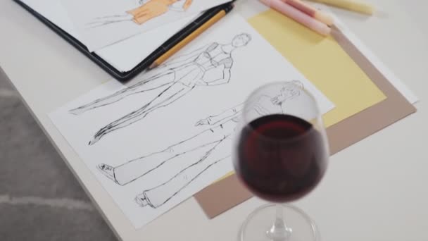 设计师工作台上的红酒 时装草图 纸张和色彩调色板的高角镜 — 图库视频影像
