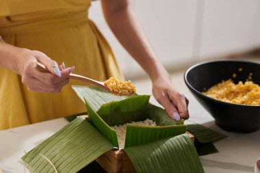 Woman putting spoon of stuffing in sticky rice cake