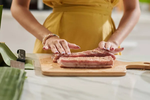 Closeup image of woman rubbing meat with seasoning