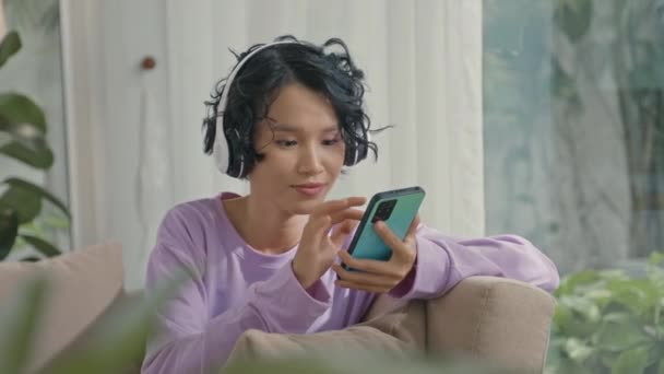 Середній Постріл Азіатської Дівчинки Геном Відпочиває Вдома Дивані Користуючись Смартфоном — стокове відео