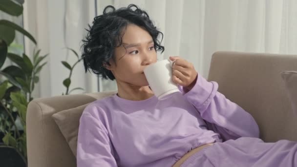 Asian Gen Girl Chilling Sofa Home Drinking Tea Mug Typing — Vídeos de Stock
