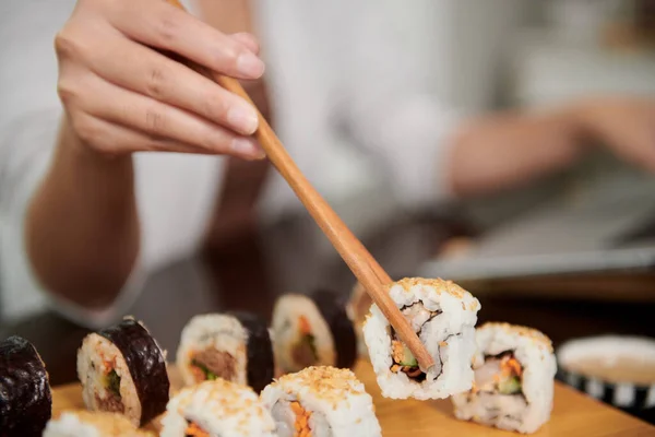 Closeup image of woman eating sushi with chopsticks