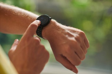 Closeup image of mature sportsman checking fitness tracker on smartwatch