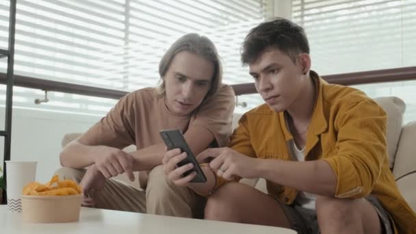 Two Caucasian Male Friends Looking Smartphone Chatting While Hanging Out — Vídeos de Stock