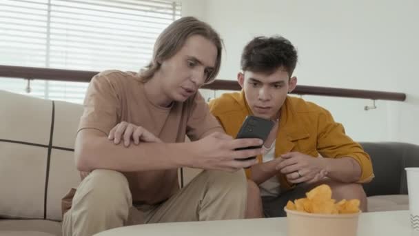 Two Mates Early 20S Eating Junk Food Discussing Something Smartphone — Vídeo de stock