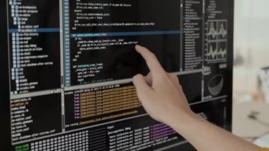Unrecognizable software developer reading program code on black screen of computer monitor