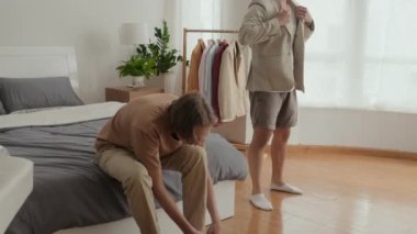 Tilt up shot of two male friends in their early 20s getting dressed in bedroom before going out