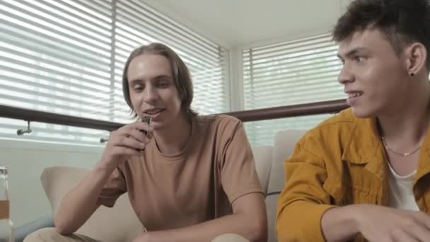 Two Best Mates Early 20S Sitting Couch Apartment Smoking Cigarette — 图库视频影像