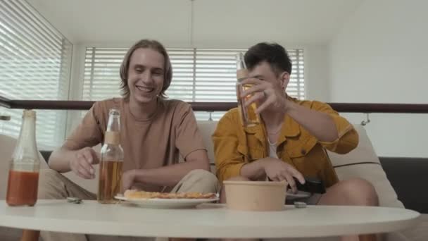 Two Buddies Early 20S Drinking Beer Watching Sitting Couch Bright — Stock Video