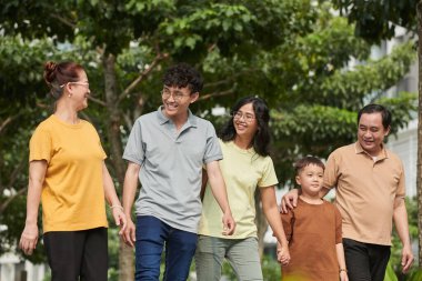 Joyful Vietnamese family walking in city park, spending weekend together