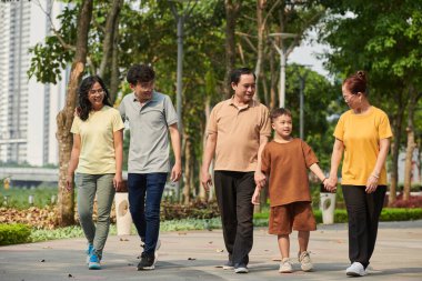 Family of three generation walking in city park on Saturday evening