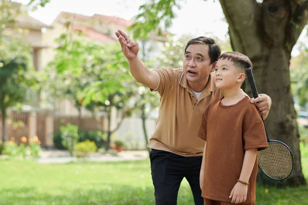 Bedstefar Forklarer Lille Dreng Hvordan Man Spiller Badminton - Stock-foto