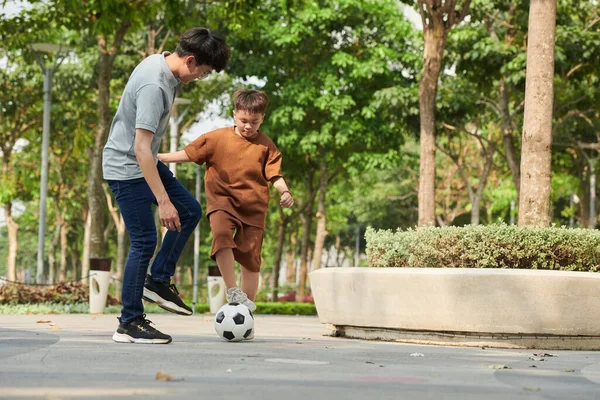 Father and son playing soccer in park on Saturday morning