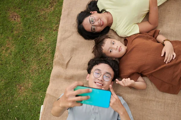 Smiling Man Resting Blanket Wife Preteen Son Taking Selfie — 스톡 사진