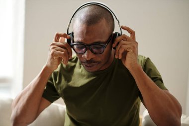 Man in glasses putting on headphone to listen to music