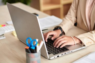 Hands of female entrepreneur typing on laptop when working in office