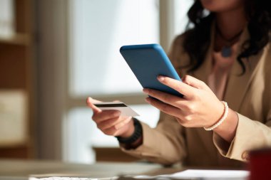 Hands of woman paying with credit card when shopping online via app on smartphone