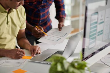 Front end developer writing ideas on sticky notes when talking to UX designer