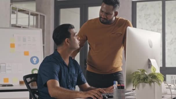 インドのIt専門家は オフィスの同僚に歩いて オープンスペースオフィスで共同作業しながら コンピュータ上のプロジェクトについてアドバイスを与えます — ストック動画