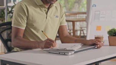 Tilt up shot of Indian mobile app developer in casual outfit drawing sketch and then posing for camera with smile at workplace in IT company office