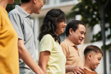 Joyful family of five walking in sunny city park