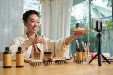 Happy blogger showing striped soap bar she made from organic ingredients