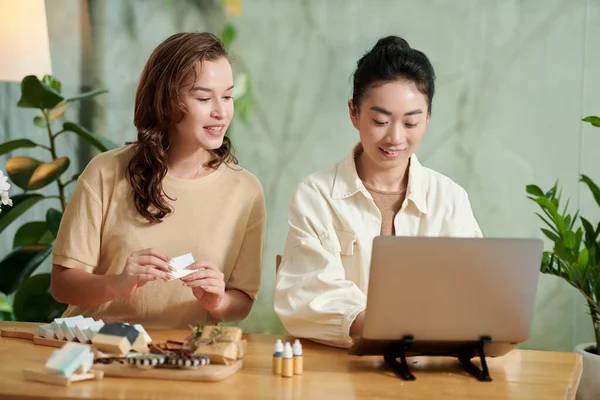 Joyful young women checking orders in online organic cosmetics shop