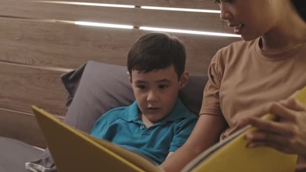 Asiática Madre Lectura Libro Junto Con Poco Hijo Mientras Acostado — Vídeos de Stock