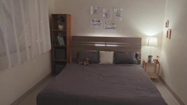 Interior of kids bedroom with drawings on wall and stuffed bear toy on bed. No people there