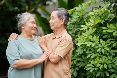 Happy senior couple in love standing outdoors and looking at each other